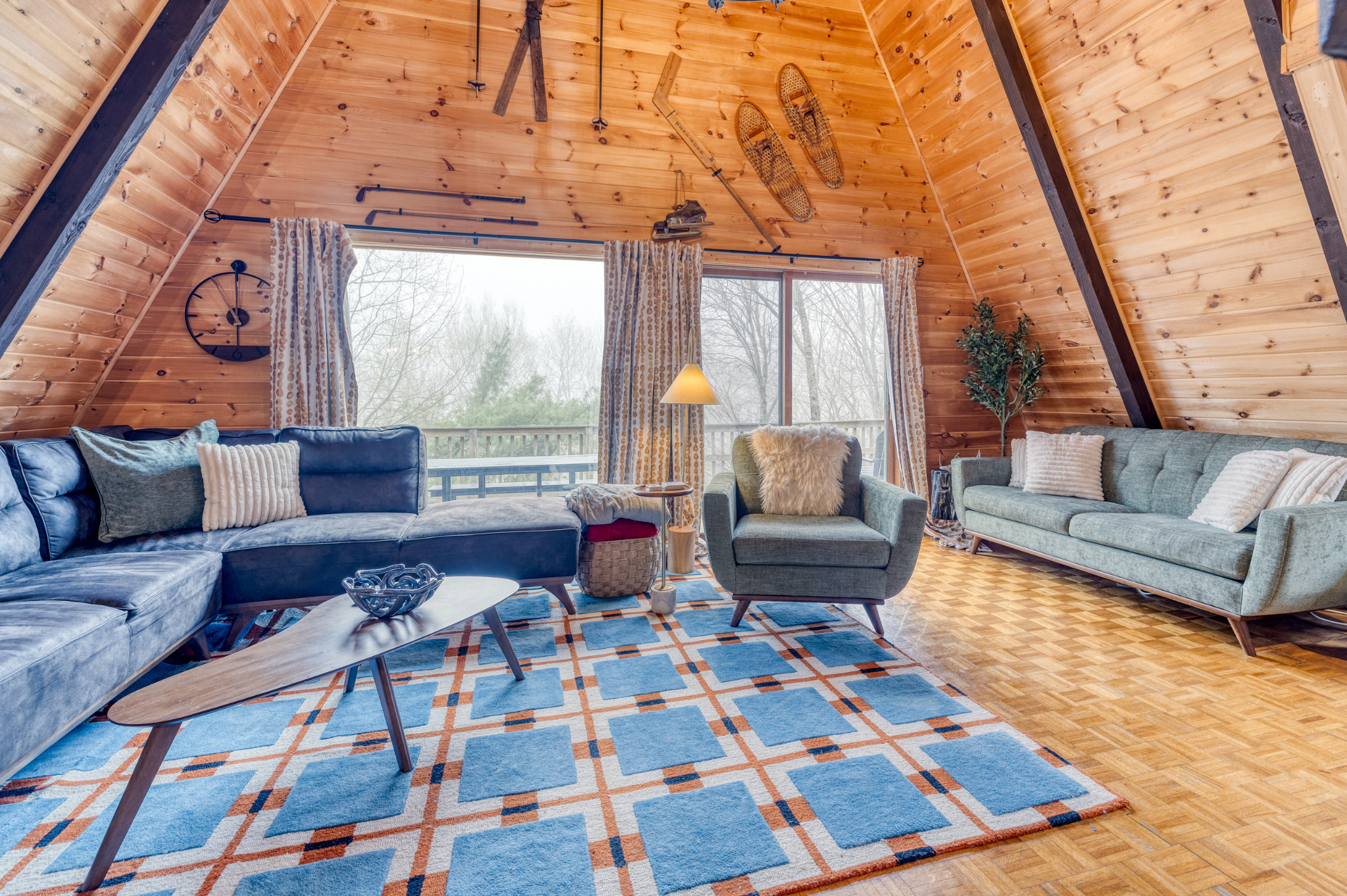 Large sliding glass doors provide access to the deck and allow natural light to flood the room, enhancing the warm and rustic ambiance.