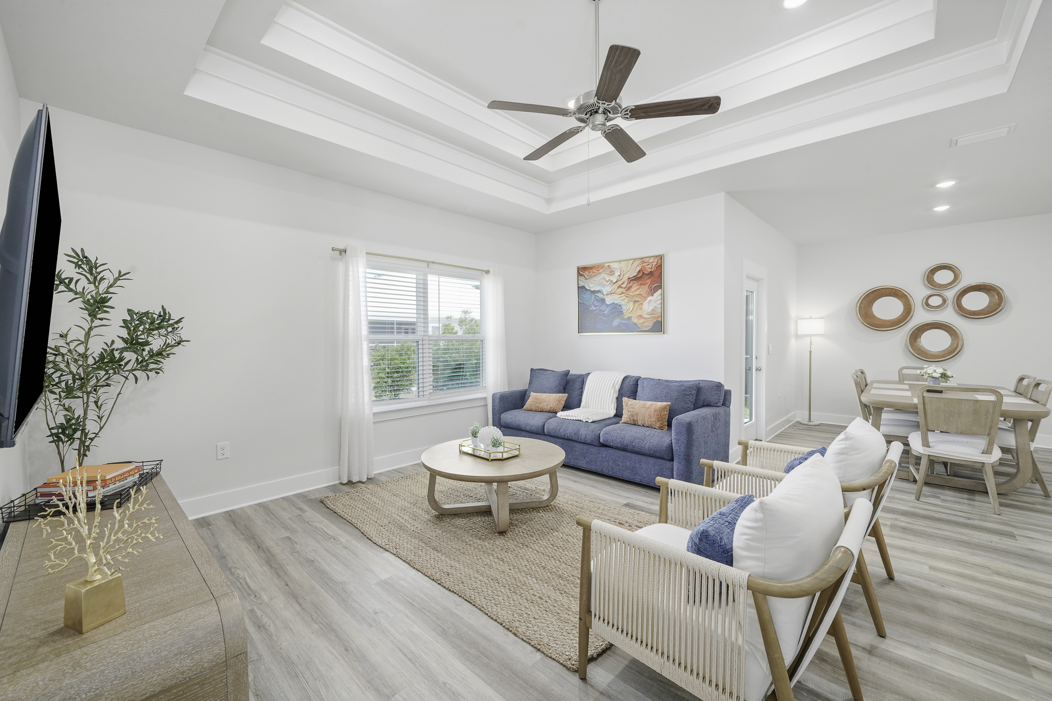Modern and airy living room with ceiling fan, Smart TV, plenty of natural light and comfortable seating