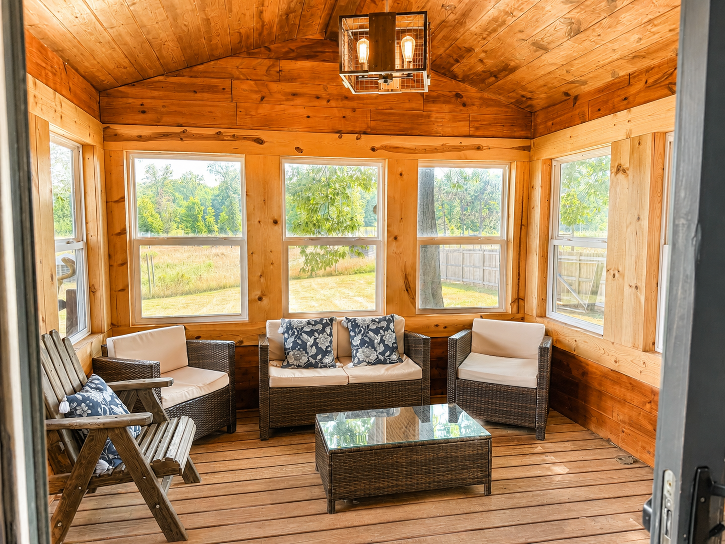 Bright enclosed sunroom just off the living room with walls of windows offers a peaceful place for morning coffee, conversation and enjoying the scenery.
