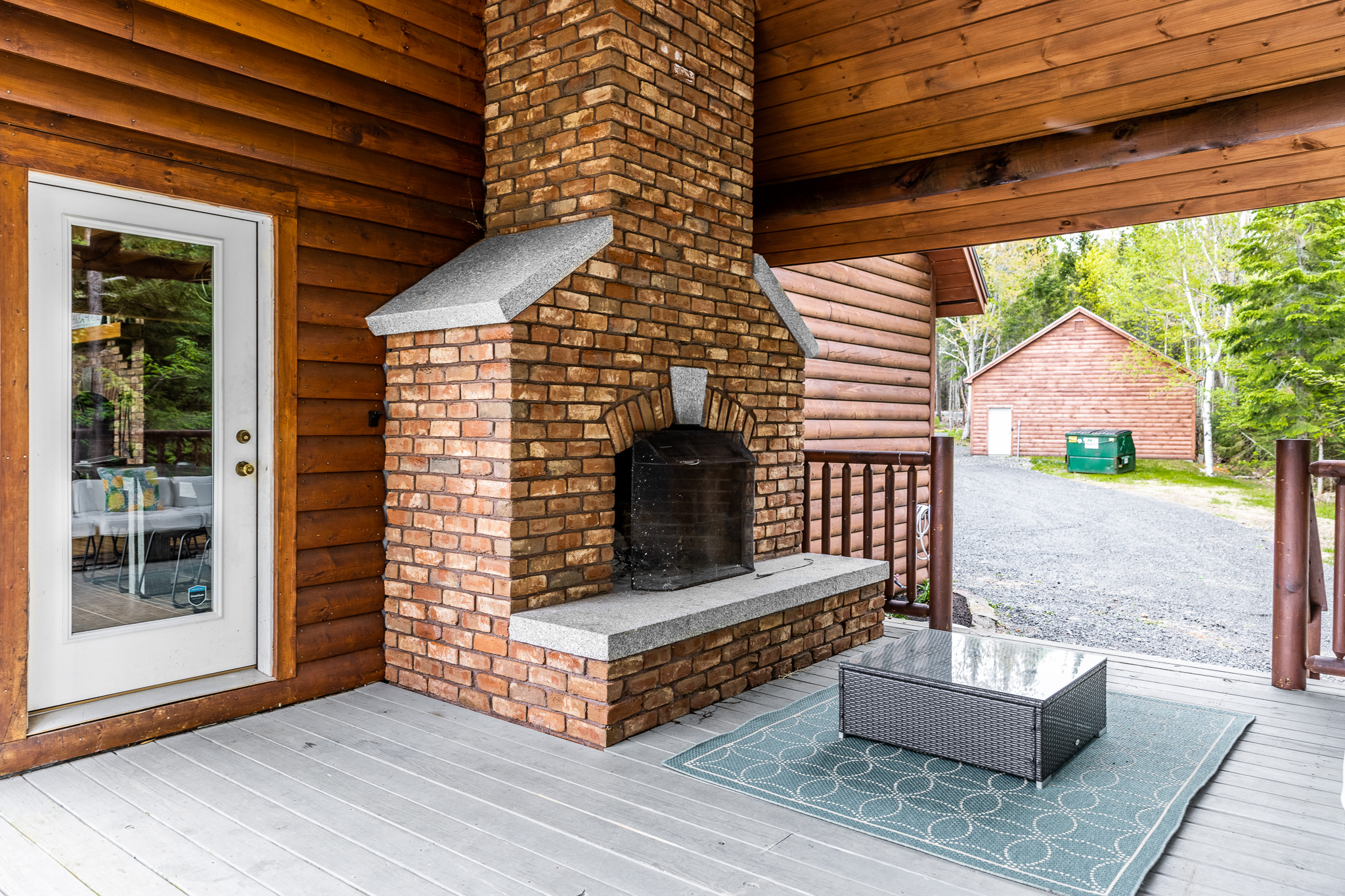 Outdoor fireplace with a seating area overlooking the lake equipped with gas grill, outdoor table for meals and covered by the roof so you can enjoy it rain or shine.
