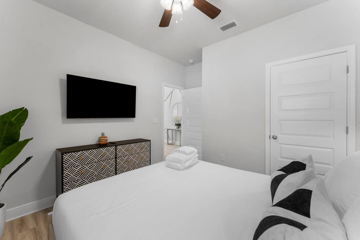 Modern bedroom with TV, ceiling fan, and elegant bedside table lamps.