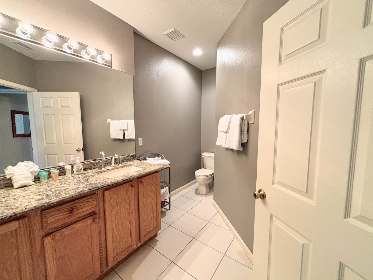 Spacious bathroom featuring a large vanity, granite countertop, tile flooring, and clean neutral finishes.