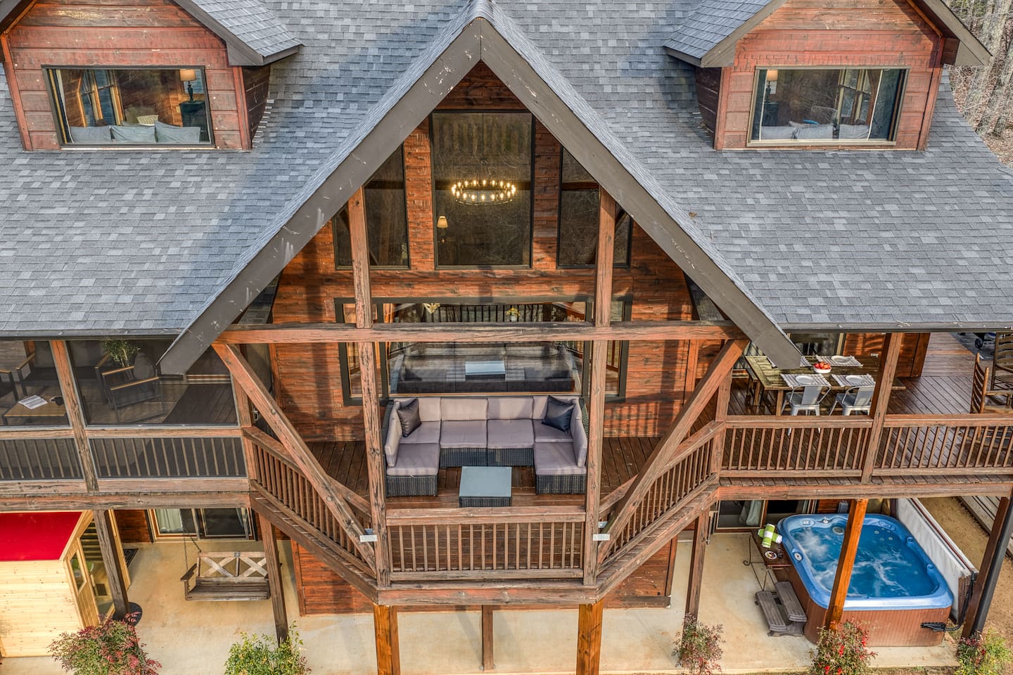 The back of the beautiful "Blessed Sunset" mountain retreat home overlooking the back yard! Stunning A-frame, wrap-around porch, screened-in patio, outdoor fireplace, outdoor dining table, sauna, hot tub, outdoor couch, and more!