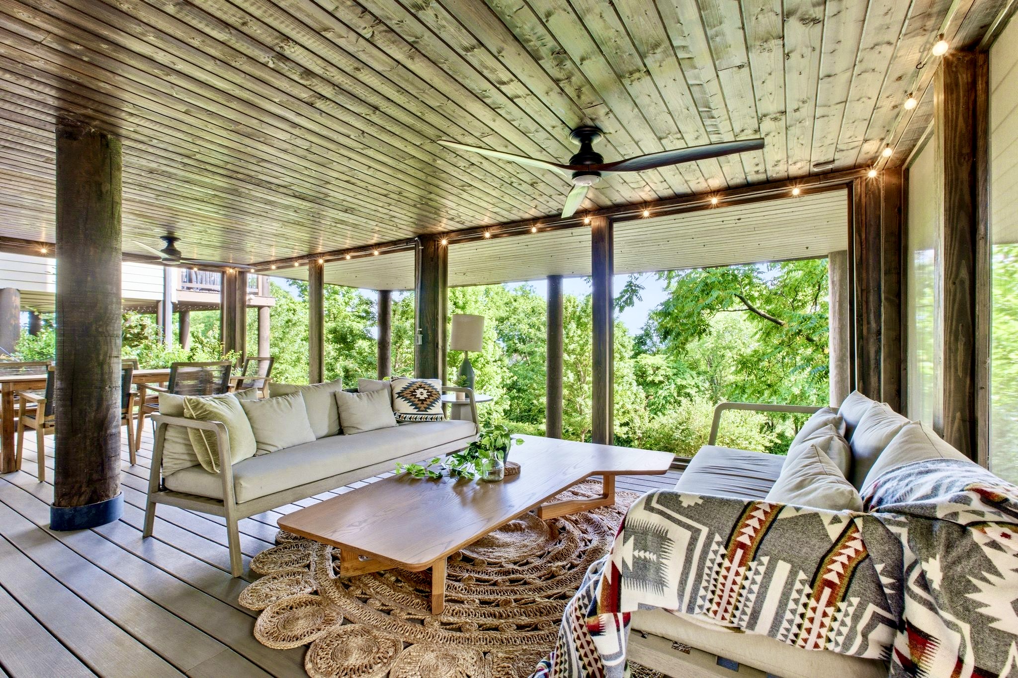 Shaded wraparound porch w/ wicker seating & treetop surroundings perfect for unwinding outdoors.
