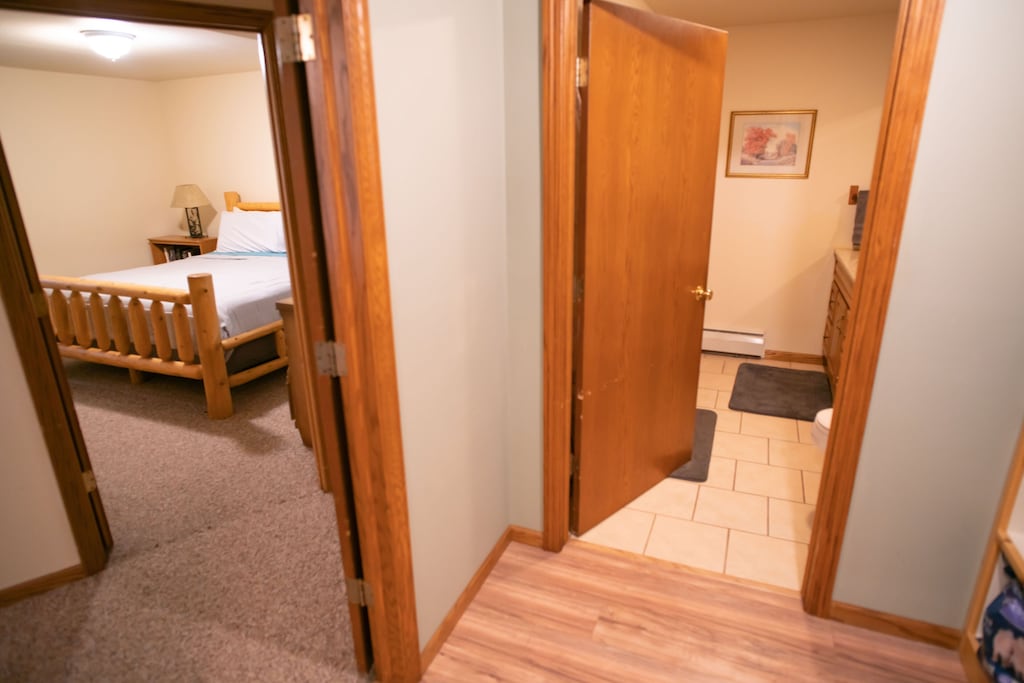 At bottom of stairs, showing bedroom 1 in lower level and bathroom