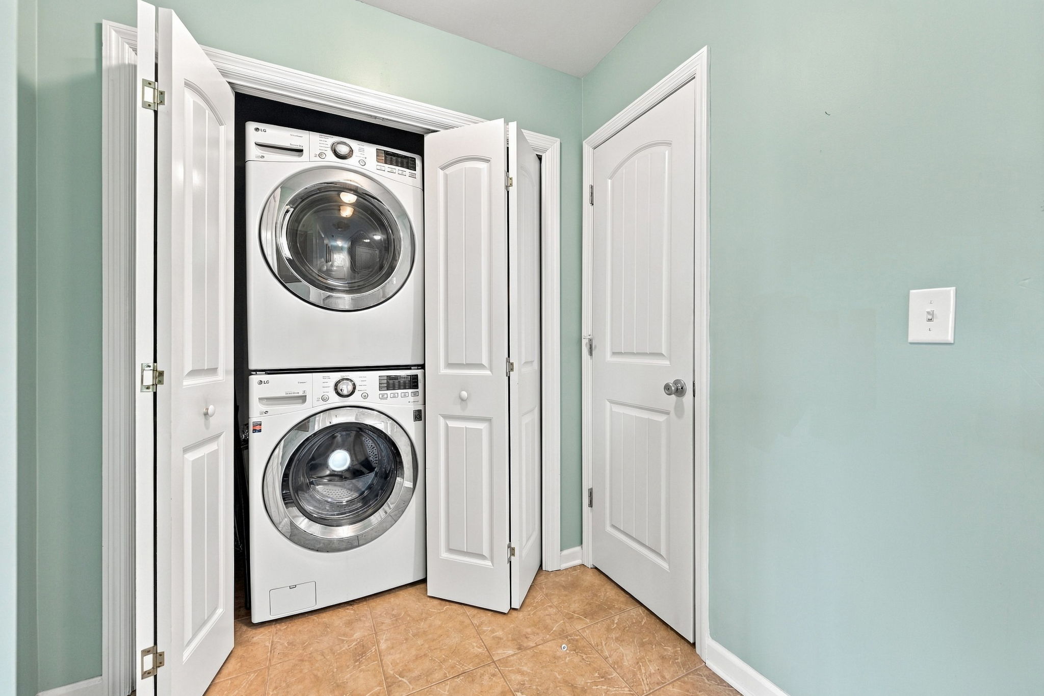 Convenient in-home laundry area featuring a full-size stacked washer and dryer