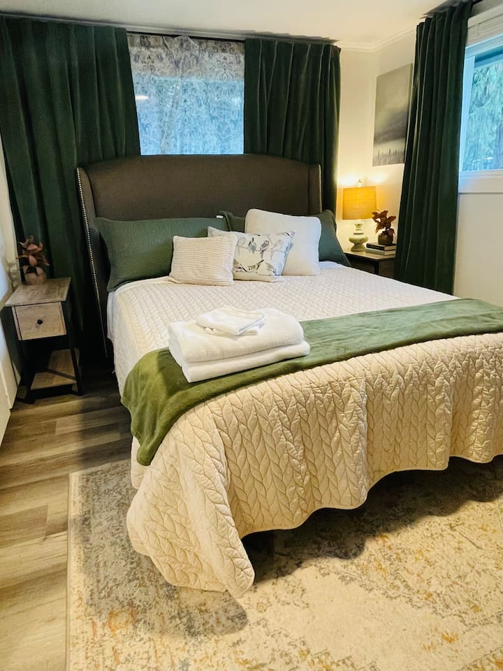 A serene queen bedroom featuring a TV and a calming nature-inspired theme with birds, blending soft patterns and layered elements for a restful retreat.