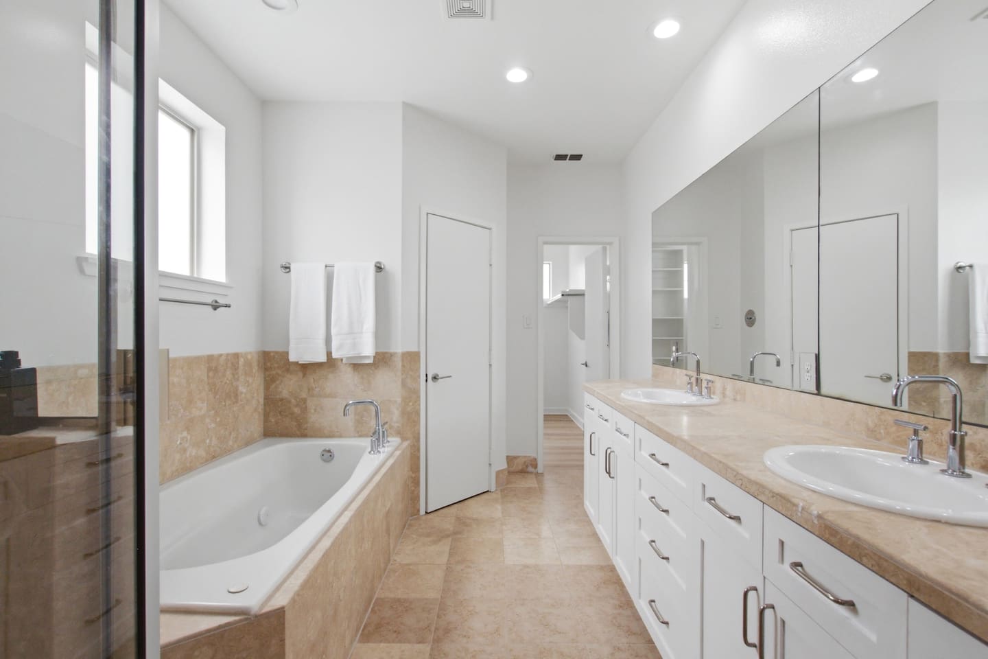 Full bathroom with soaking tub, double vanity, and warm tile finishes. Stocked with Ginger Lily Farms bath essentials so you can settle in without a pharmacy run.

