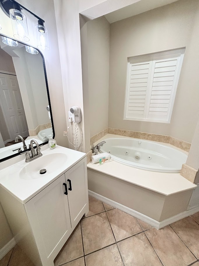 Bathroom vanity and soaking tub area with clean neutral finishes and tile flooring.