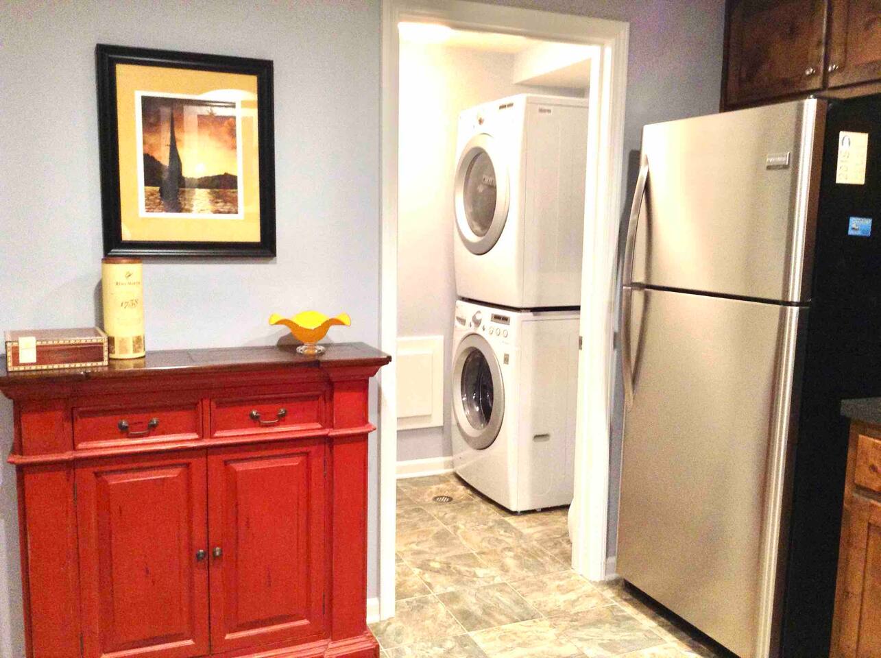 Stainless steel refrigerator with ice maker, with newer front load washer and dryer in laundry room. 