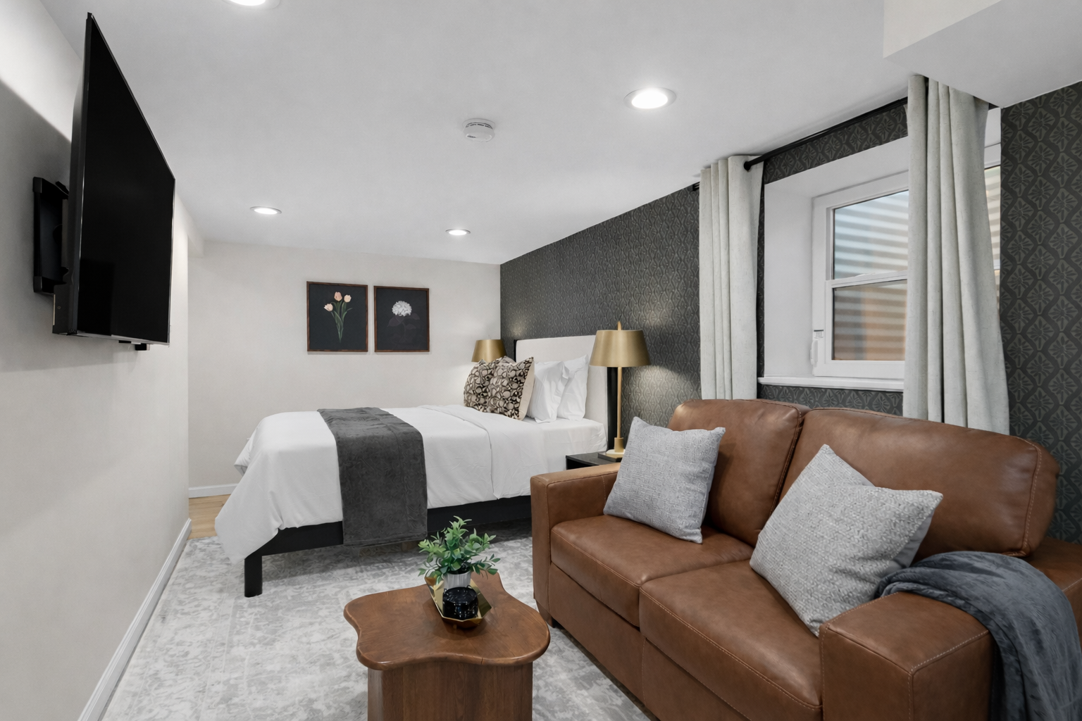 Stylish studio retreat featuring a plush bed, cozy leather seating, soft lighting, and smart TV—thoughtfully designed for comfort and a relaxing stay.