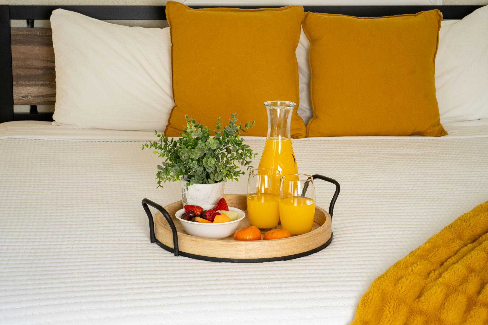 A cozy bed with mustard accents and a sleek black sofa create a stylish retreat with direct access to the outdoors.