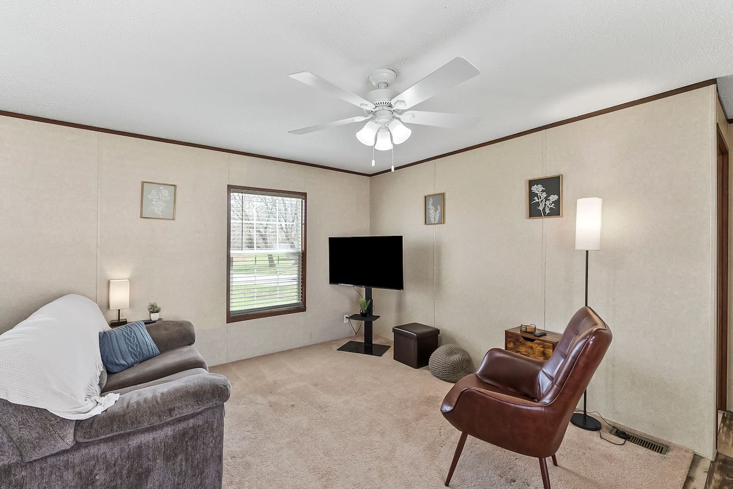 Bright and cozy living room with Smart TV, comfortable seating, and large window for natural light.
