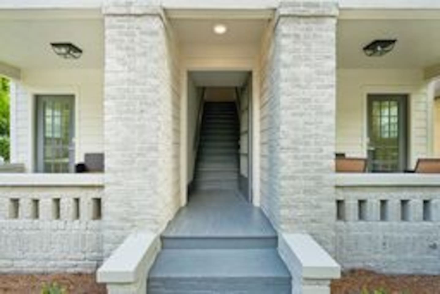 The middle doorway leads to a flight of stairs. The stairs lead to Units 3 & 4. The welcoming entryway to the building features a traditional porch that adds a touch of Southern charm.