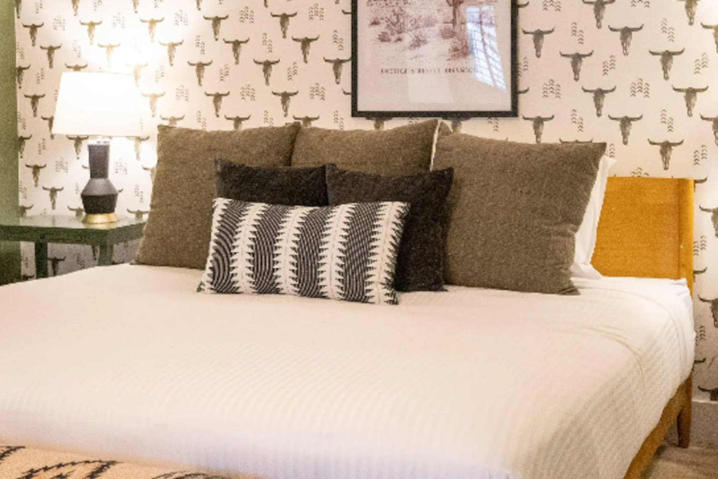 A king bed layered in rich textures, framed by playful ranch-inspired wallpaper — Southwest charm with a boutique-hotel feel.