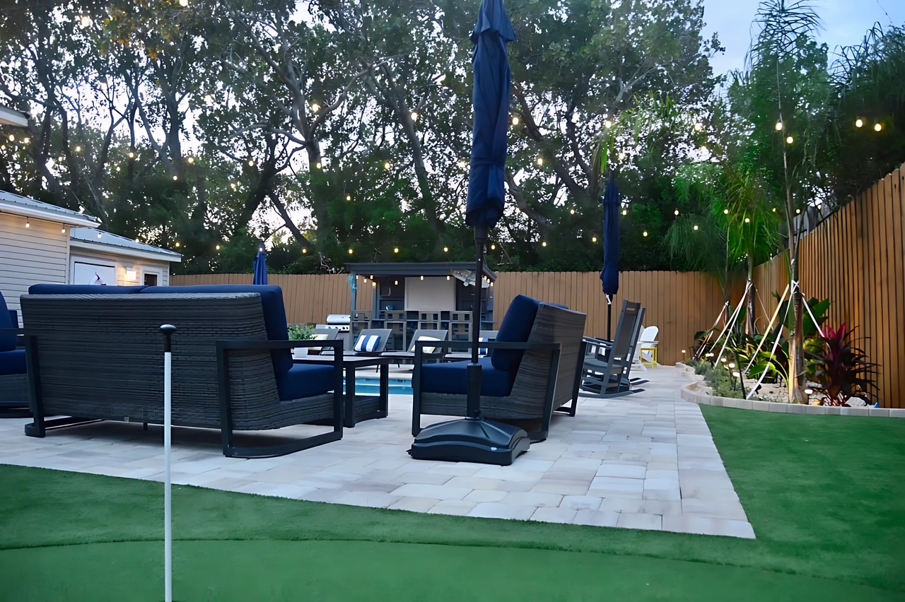 Daytime view of the expanded patio, new seating, upgraded landscaping, putting green and lighting