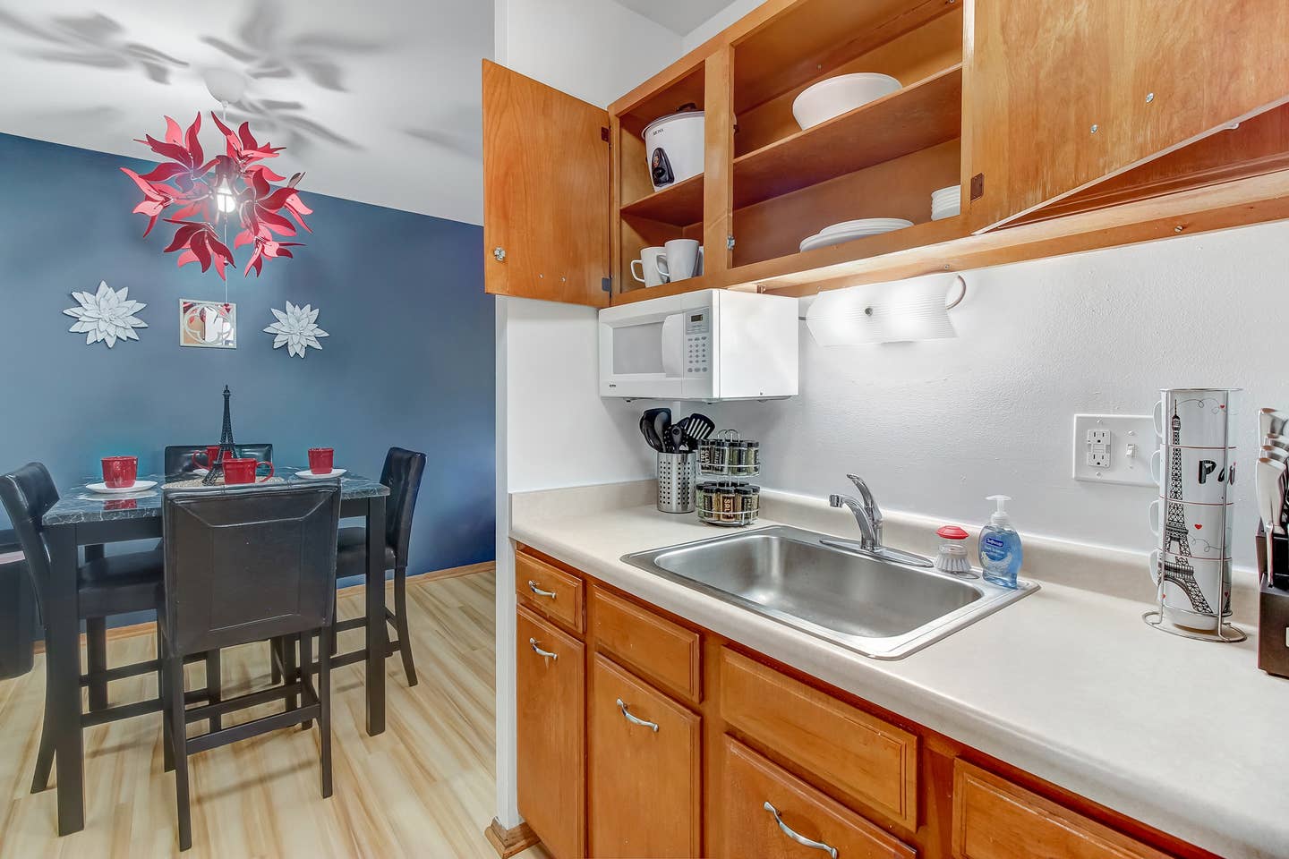 Plenty of plates, bowls, cups and cooking utensils and there is a rice cooker and microwave.