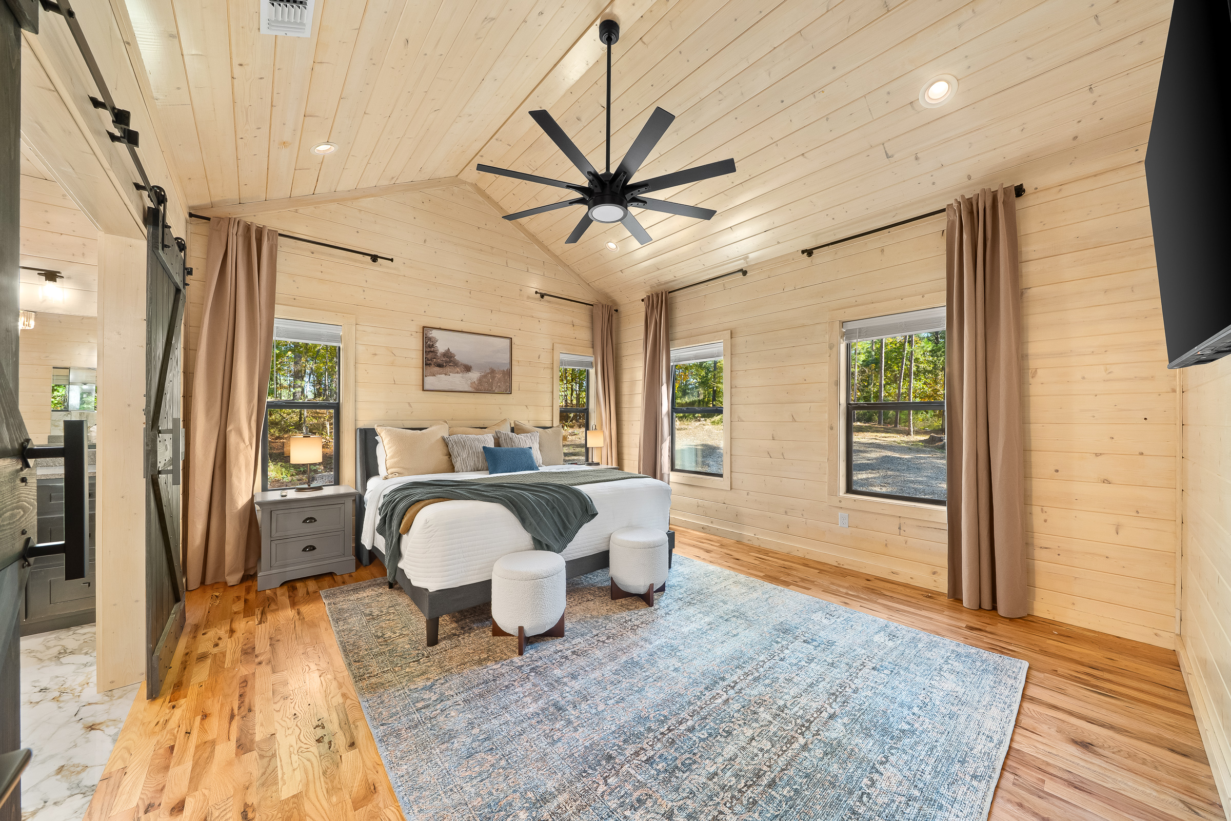 Soft lighting, plush bedding, and a layered rug create a calm king retreat ready for unwinding with a drink and your favorite show.