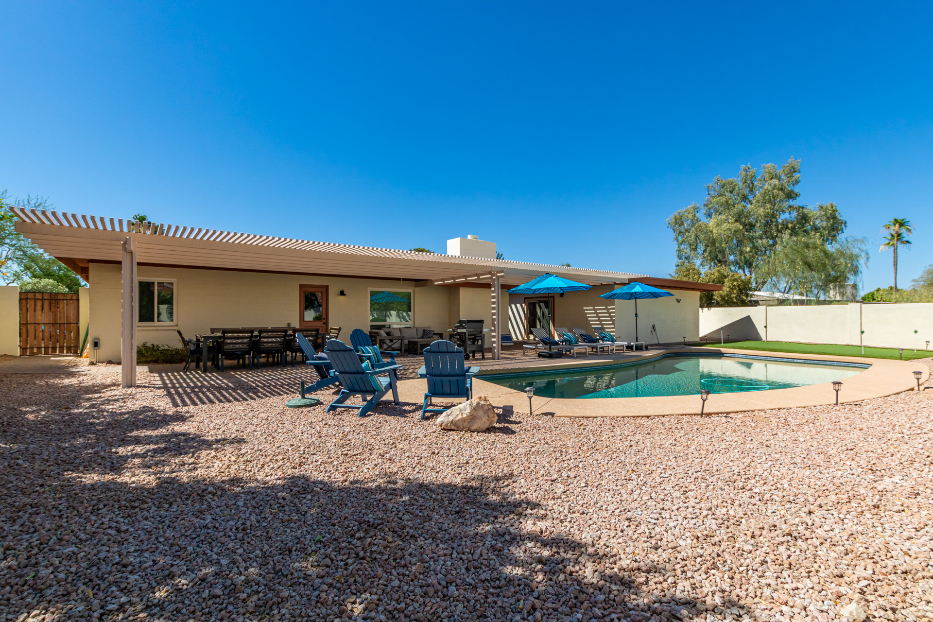 awesome backyard with sparkling pool, newly installed putting green, outdoor dining + lounge seating + corn hole