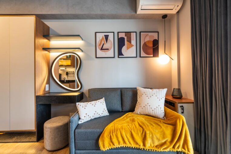 Sofá-cama confortável, ar-condicionado, estação de trabalho com espelho iluminado e decoração moderna — perfeito para home office, descanso ou leitura em Pinheiros.