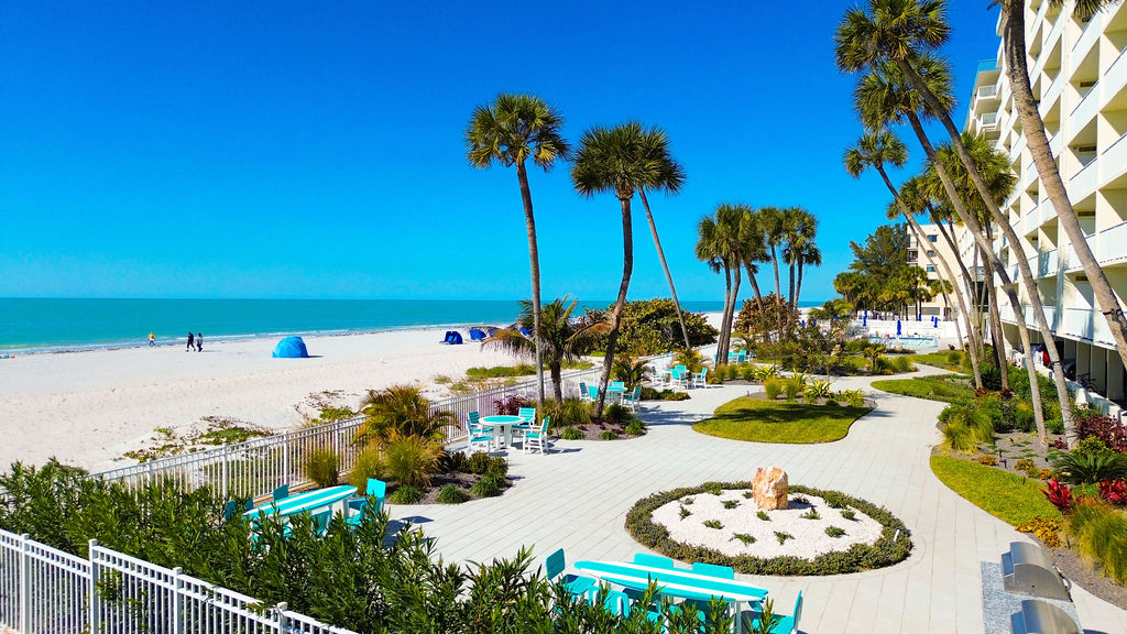 Beautiful beachfront vacation rental with lush tropical landscaping, outdoor lounge areas, and direct access to the white sand beach.