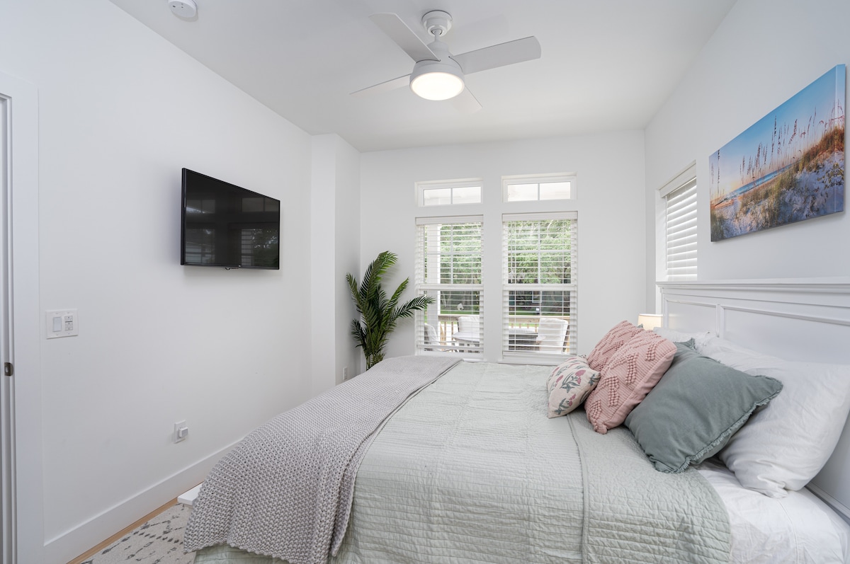 Soft green linens, a ceiling fan turning overhead, and a TV on the wall for the slowest of mornings. The blinds open toward the front porch, so most days you hear the leaves moving before you have seen the sky.