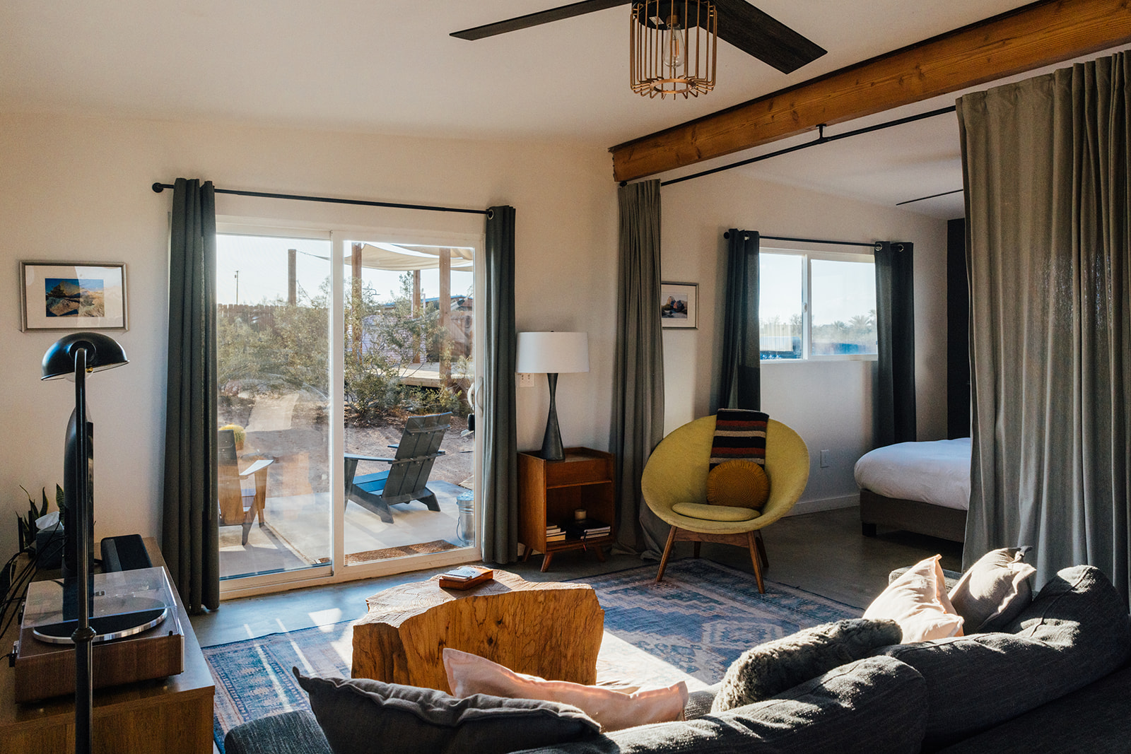Cozy desert living room with modern seating, stylish decor, and sliding glass doors that open directly to the patio and expansive Joshua Tree views.