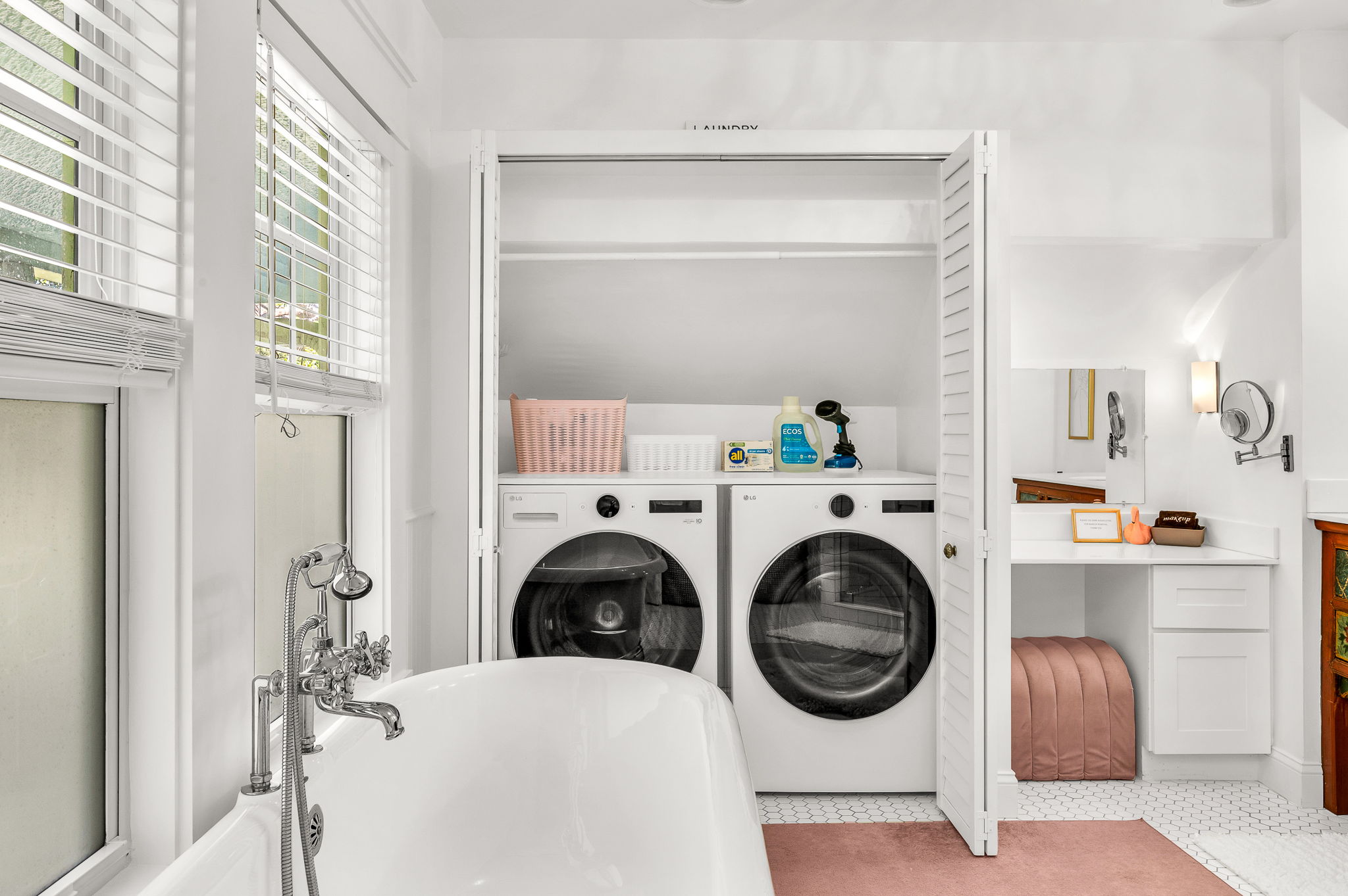 Full Bathroom #1: Elegant ensuite bath featuring an antique clawfoot soaking tub, modern glass-enclosed shower, built-in dressing table with magnifying mirror, and full-size washer and dryer tucked behind double doors.