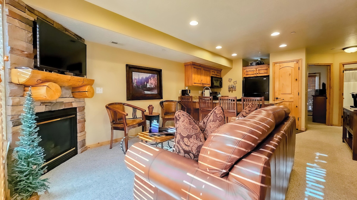 Experience the cozy living room, outfitted with plush seating, a fireplace, an expansive smart TV, and patio doors that frame the breathtaking mountain vistas.