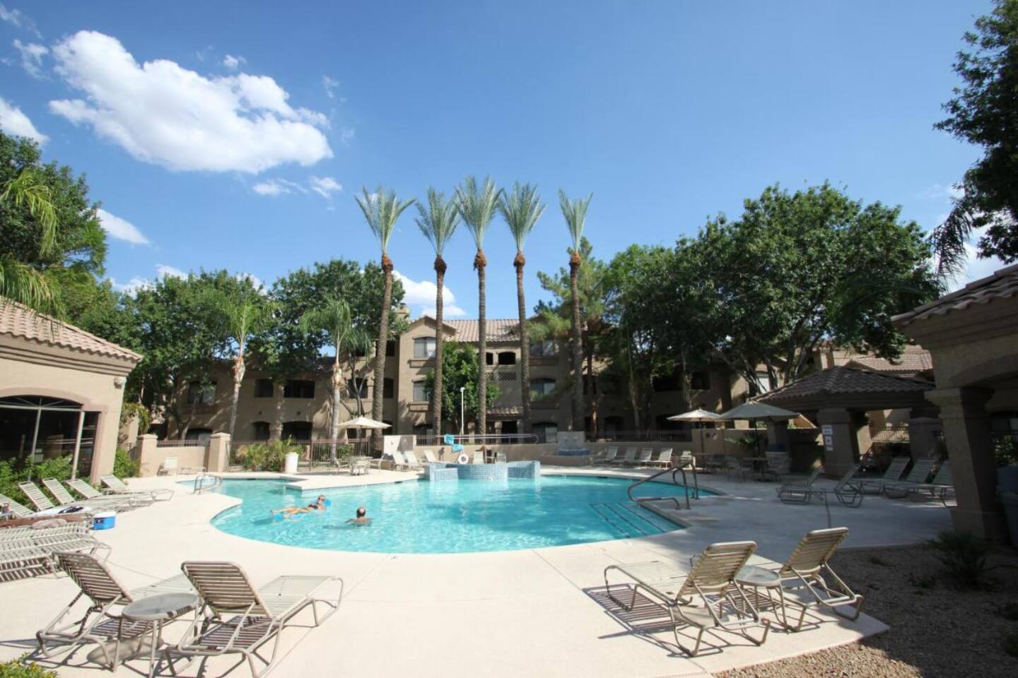 Community pool area with lounge chairs, shaded seating, and a resort-style outdoor setting.