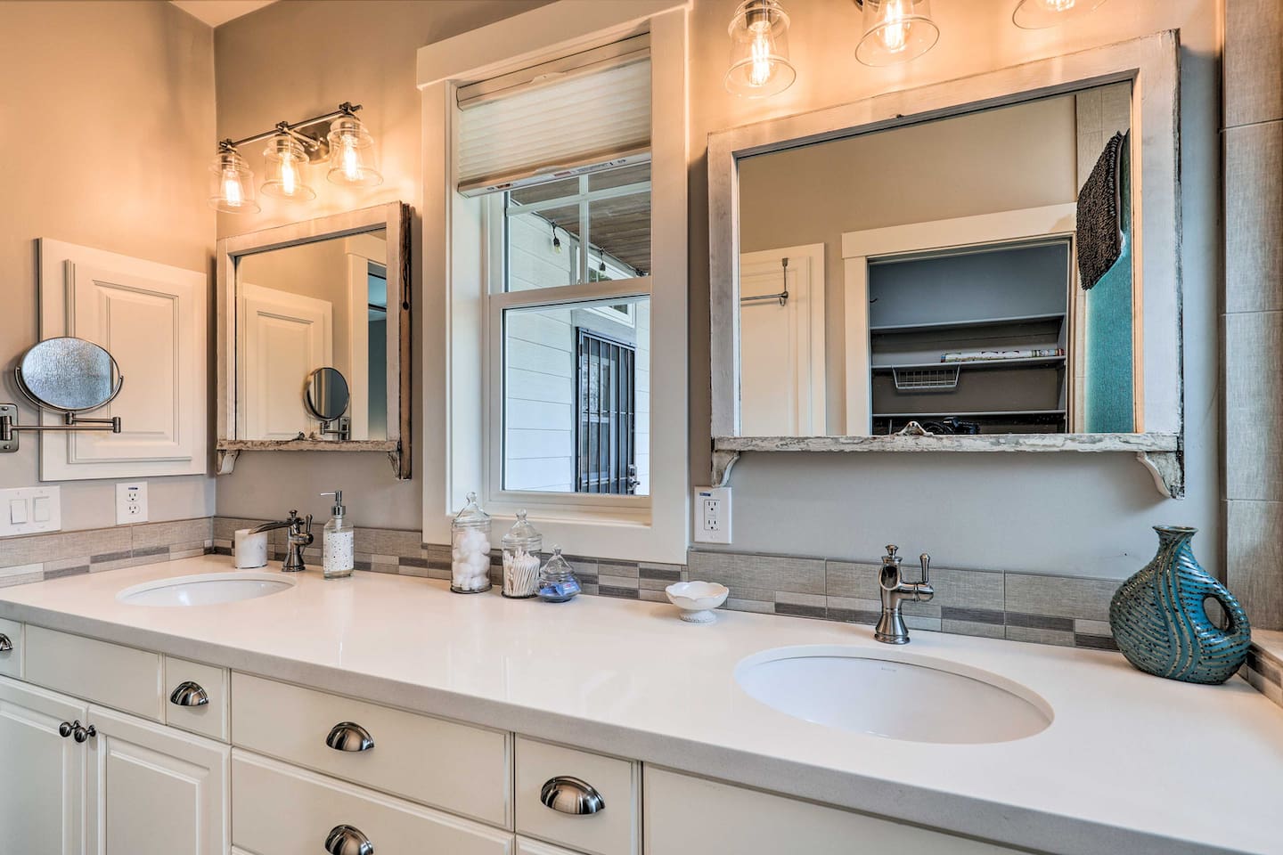 Get ready side-by-side at this stylish double vanity, framed by warm lighting and vintage mirrors.