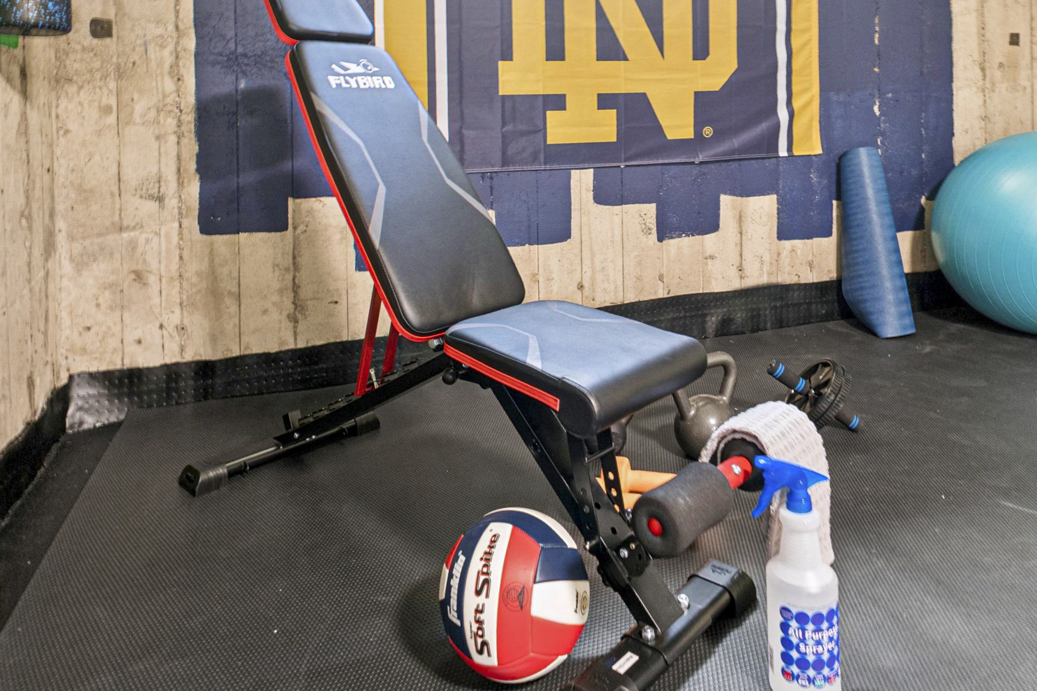 Fuel your fitness with Fighting Irish pride—our South Bend guest retreat gym features a bold ND sign, workout bench, weights, and gear to keep your crew moving near Notre Dame.