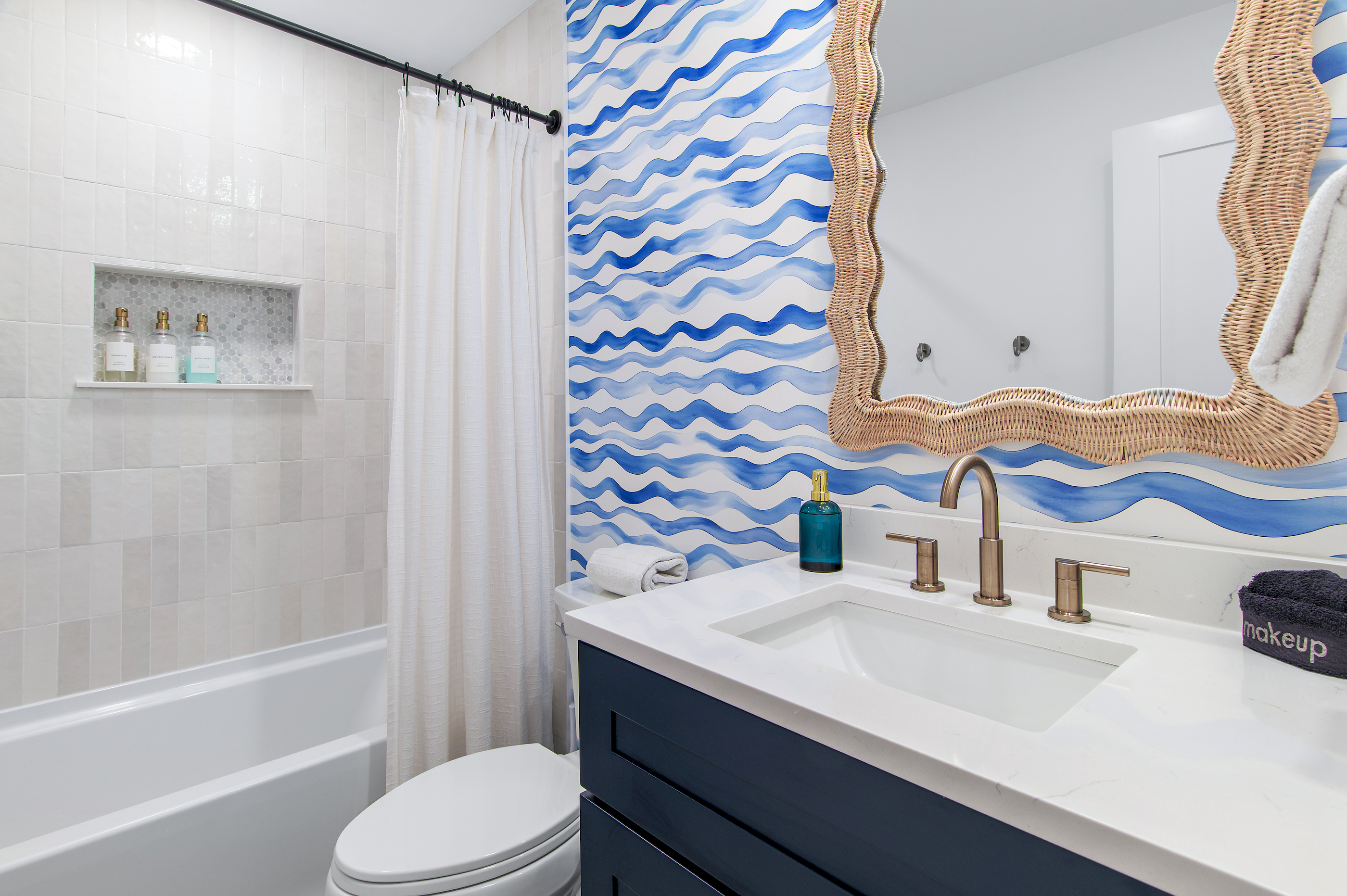 A fun, coastal-inspired bathroom with a tub/shower combo and charming wave details.