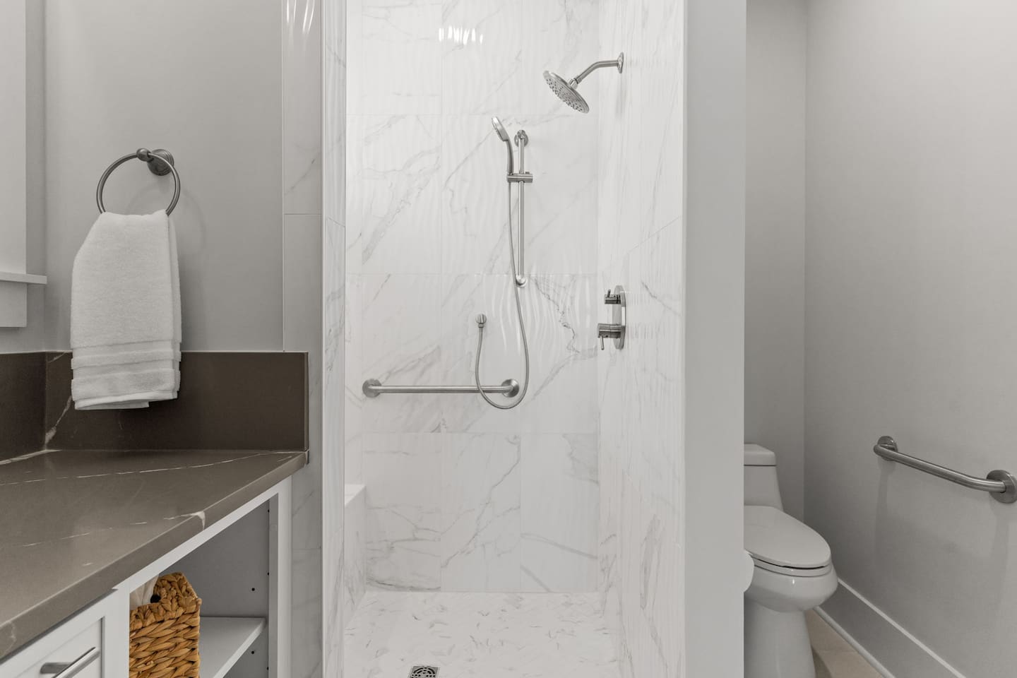 Designed with accessibility and comfort in mind, this en-suite bathroom features a curbless shower entry, shower bench, shower grab bars, and toilet grab bars to provide guests with added safety, convenience, and peace of mind throughout their stay.