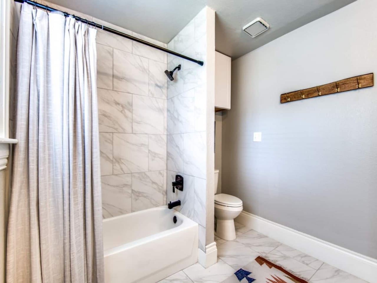 Full ensuite bathroom with tub and shower combo, tile surround, and clean white finishes. Stocked with shampoo, conditioner, and body soap. Part of the 2.5 bath layout in this modern farmhouse Airbnb near Lake Ray Roberts in Aubrey TX.
