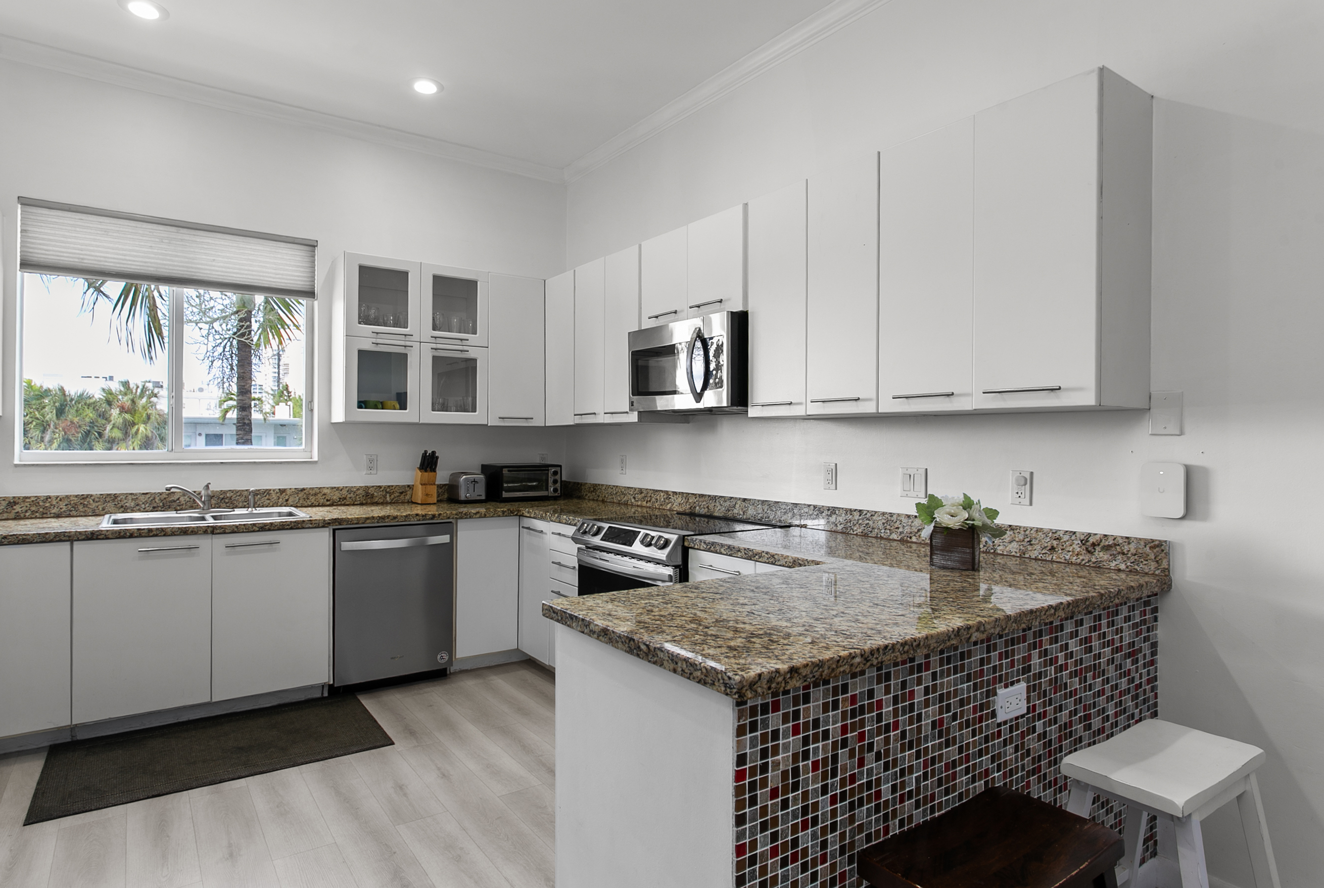 Mosaic tiled kitchen with Induction range, French door fridge and breakfast counter.