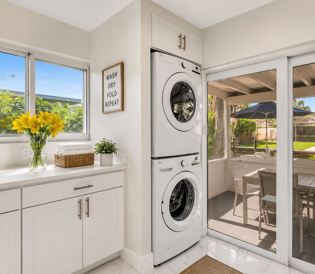 Full-size washer and dryer with built-in storage and counter space, conveniently located beside the patio.