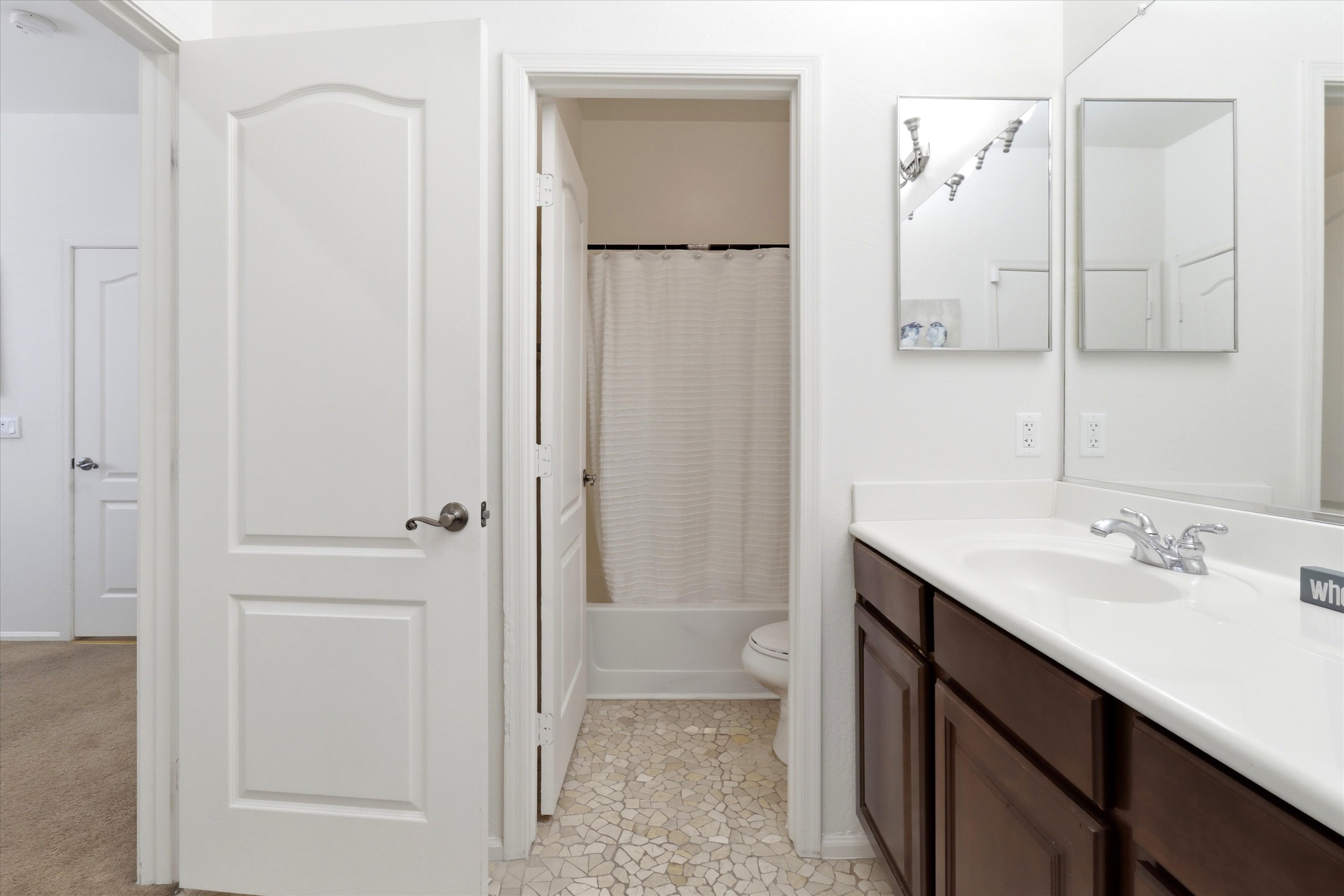 Bathroom vanity with storage cabinets and a shower/tub area just around the corner.
