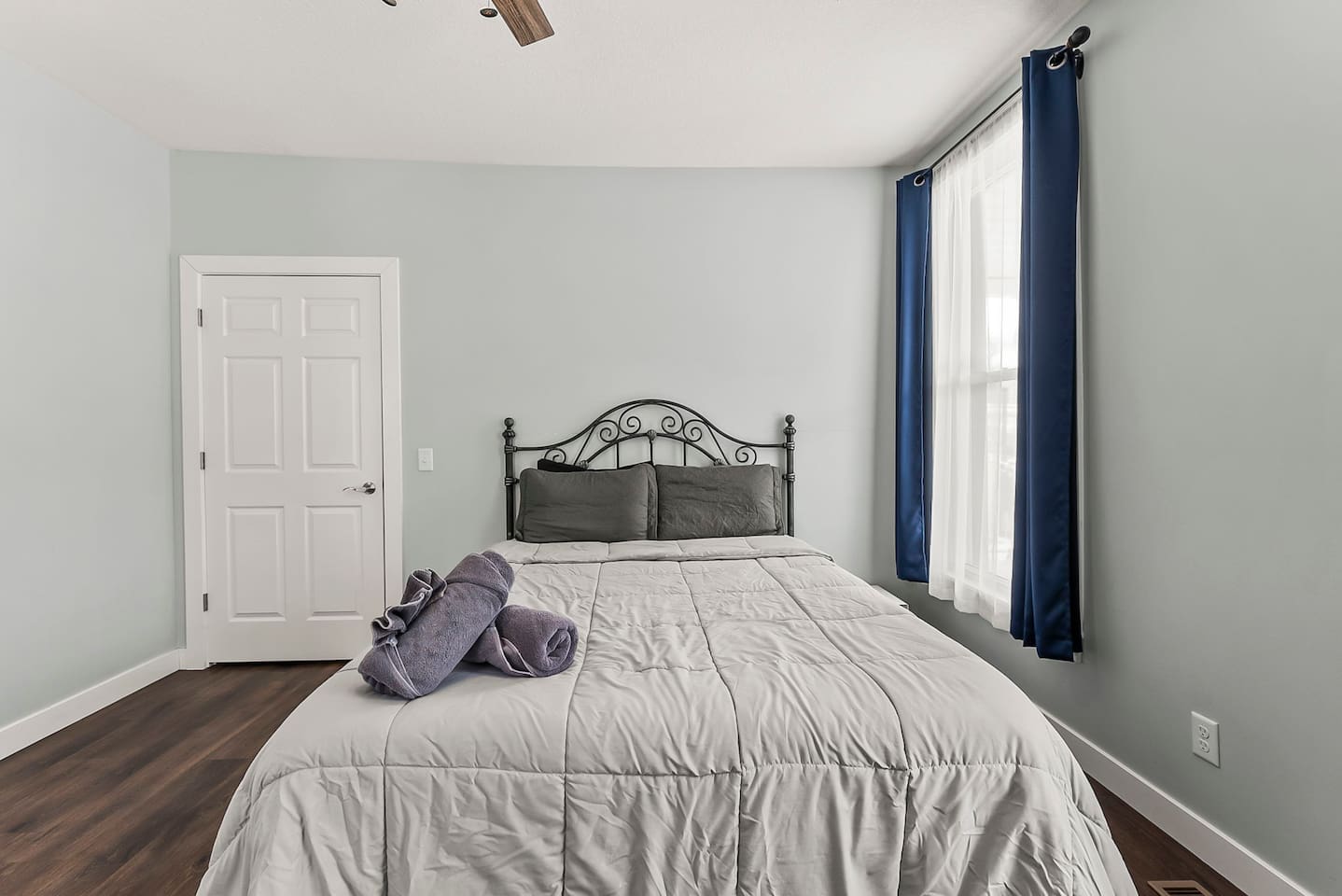 Queen bed dressed in fresh linens, paired with a ceiling fan and classic architectural details.