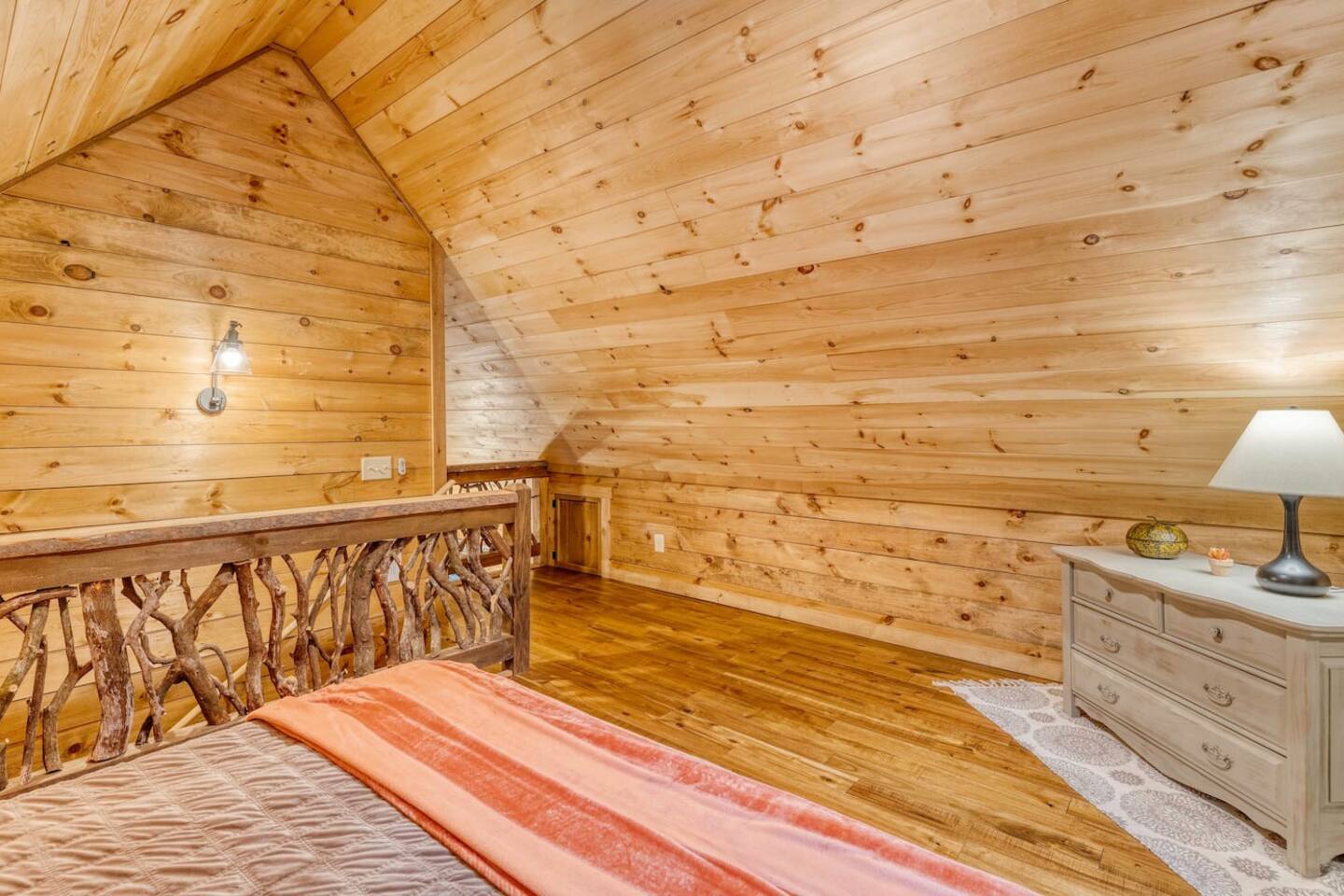 Our loft space offers a cozy bed, nestled beneath the eaves, where sloping ceilings and snug surroundings create a tranquil haven for rest and relaxation in our charming cabin retreat