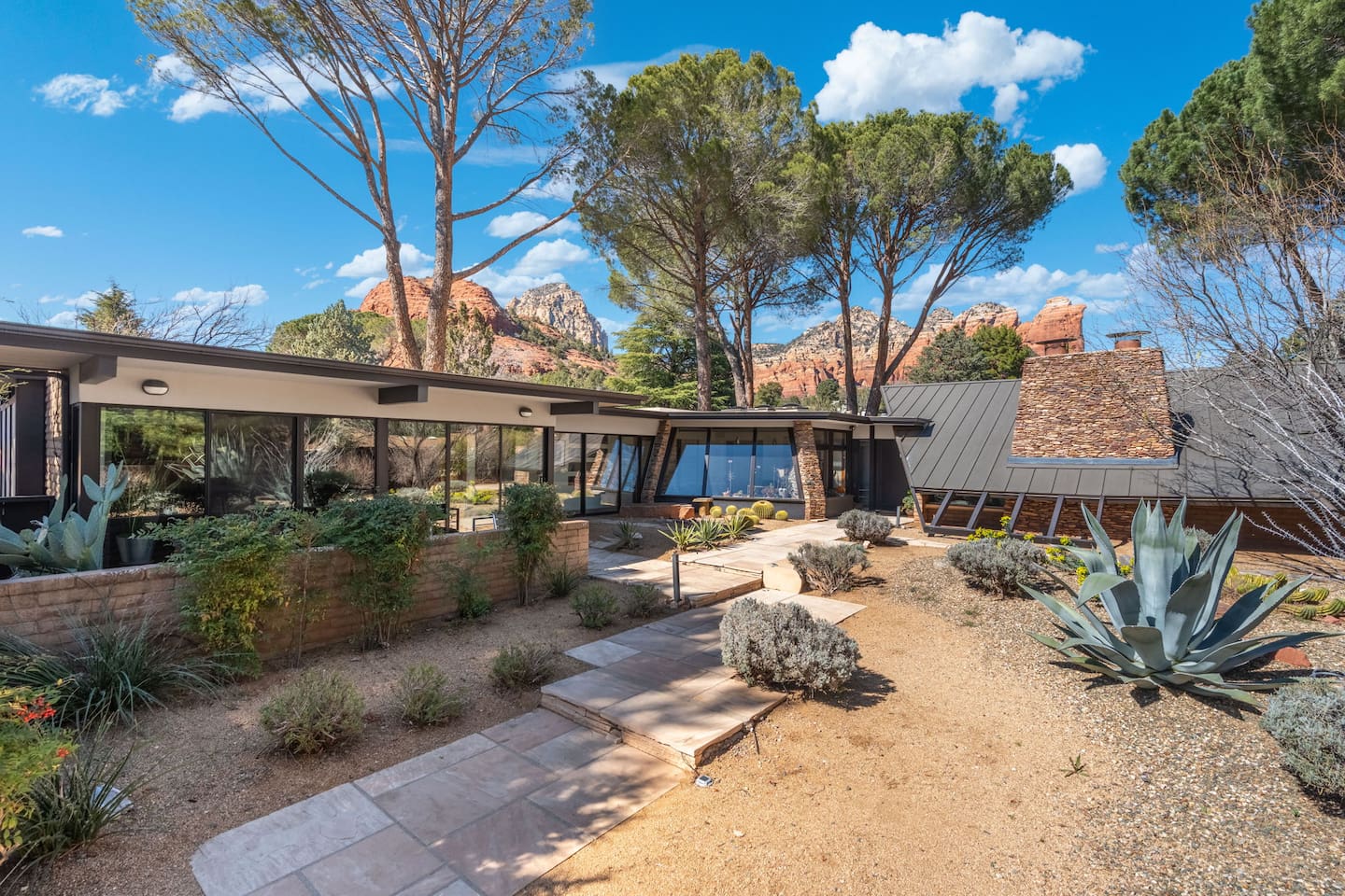 Inviting pathway leading through thoughtfully designed xeriscape gardens toward the modern home and surrounding red rock scenery.