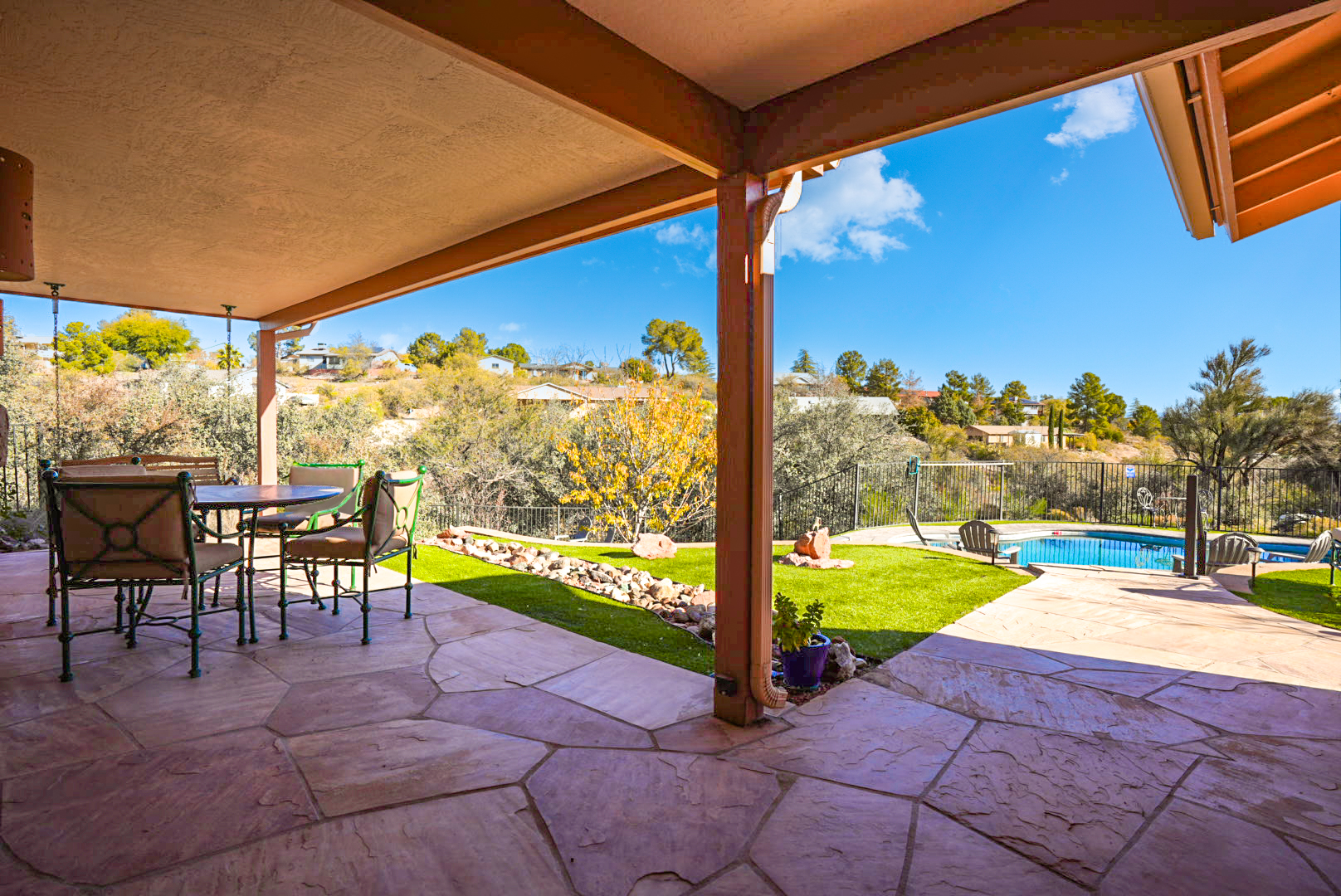 Spacious covered patio with outdoor dining and views of the pool and surrounding landscape.