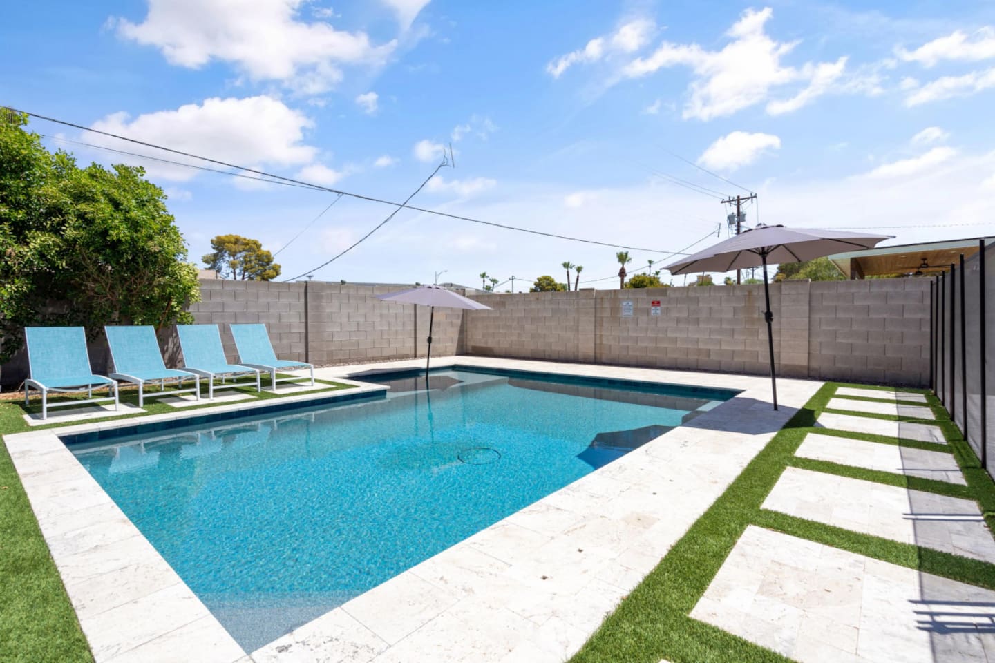 Private backyard pool with lounge chairs, umbrella shade, fire pit seating, and a bright outdoor space 