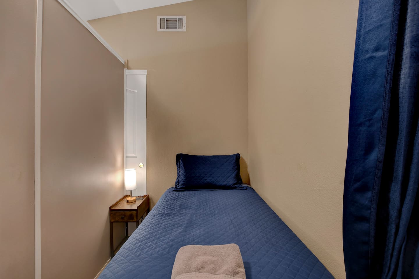 Cozy twin-bed nook with privacy curtain and bedside lamp.