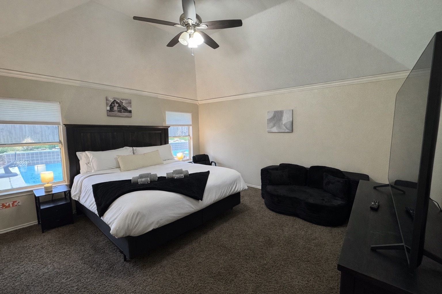 Spacious master bedroom with a king bed, vaulted ceilings, relaxing seating area, and a full sleeper sofa for extra guests.