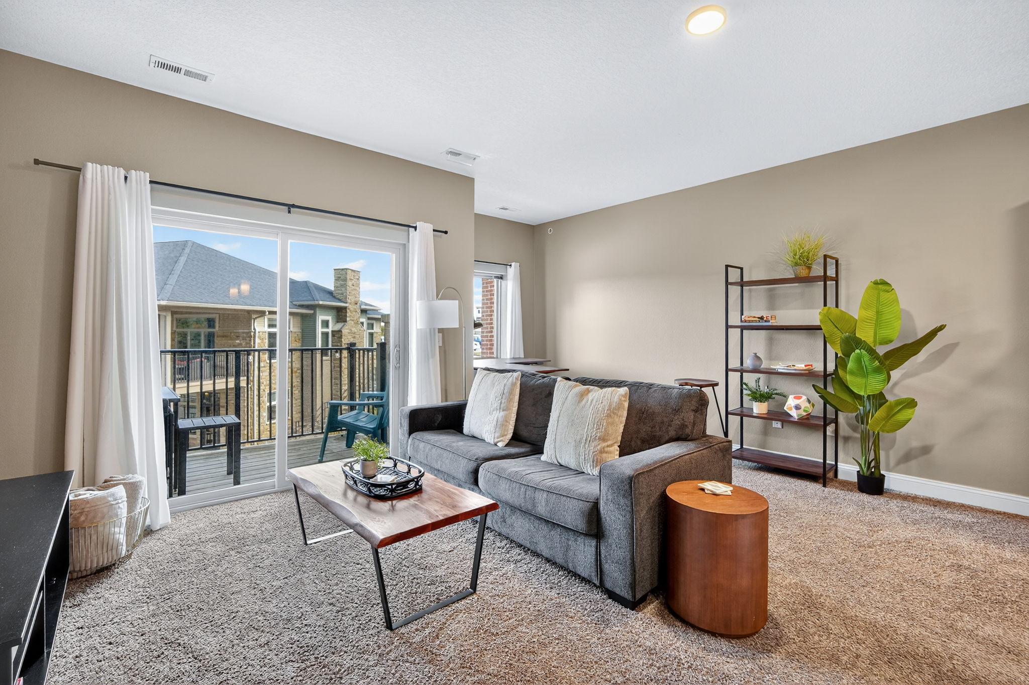 Cozy yet open, this living room connects seamlessly to the balcony and dining nook. A comfy sofa, warm accents, and modern shelving create a perfect mix of relaxation and function.