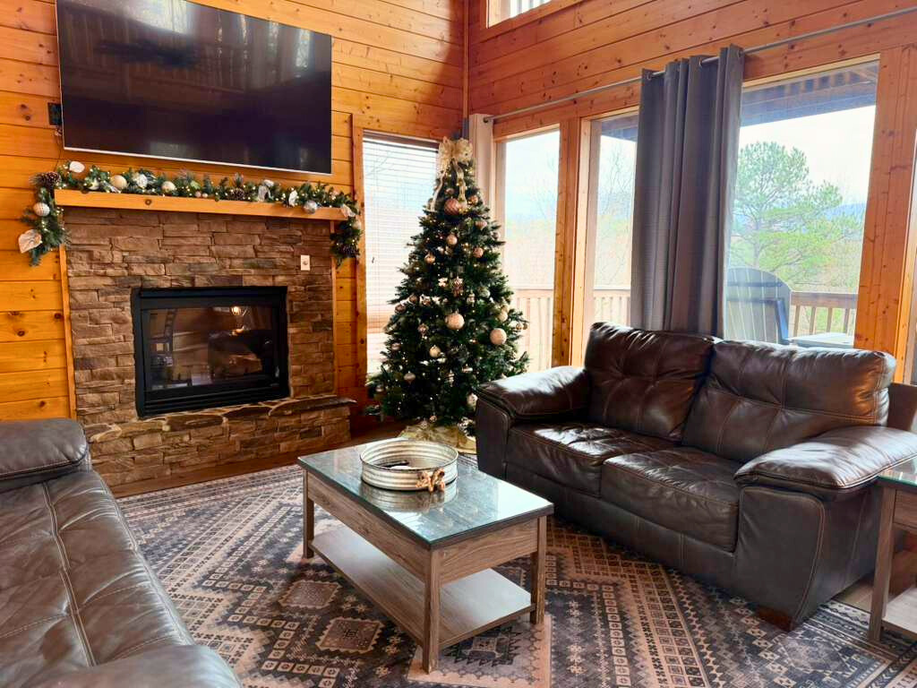 The heart of your holiday home! This spacious room, featuring stunning wood walls and a decorated tree, is ready for your festive gatherings. Unwind by the fire with a spectacular view!