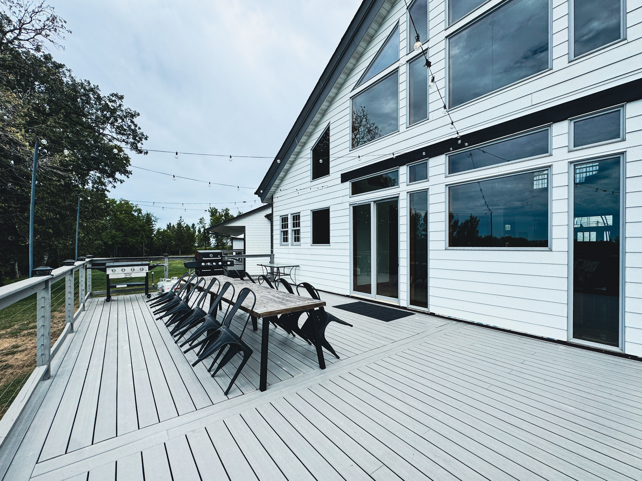 Main deck with dining seating, twinkle lights, a Blackstone grill, and a gas grill.