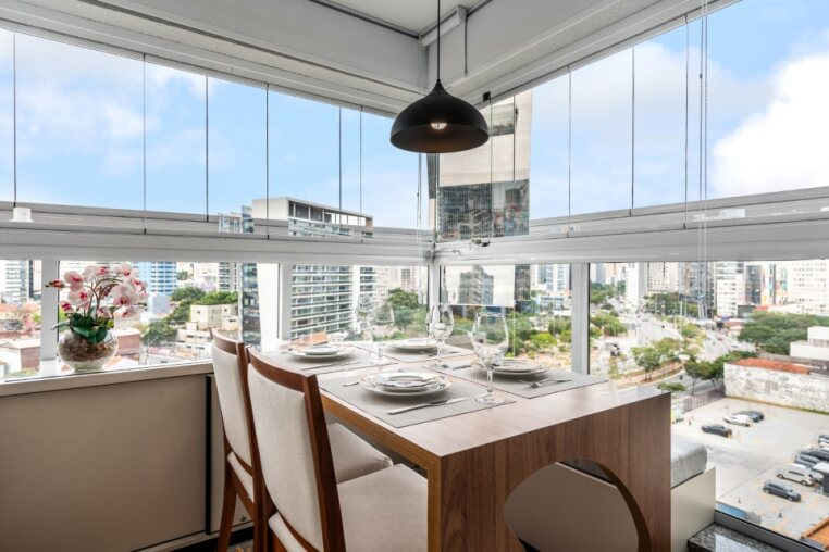Varanda envidraçada com vista panorâmica e mesa para 4 Espaço ideal para café da manhã ou jantar com vista. Mesa ampla, iluminação pendente e integração com a cidade.