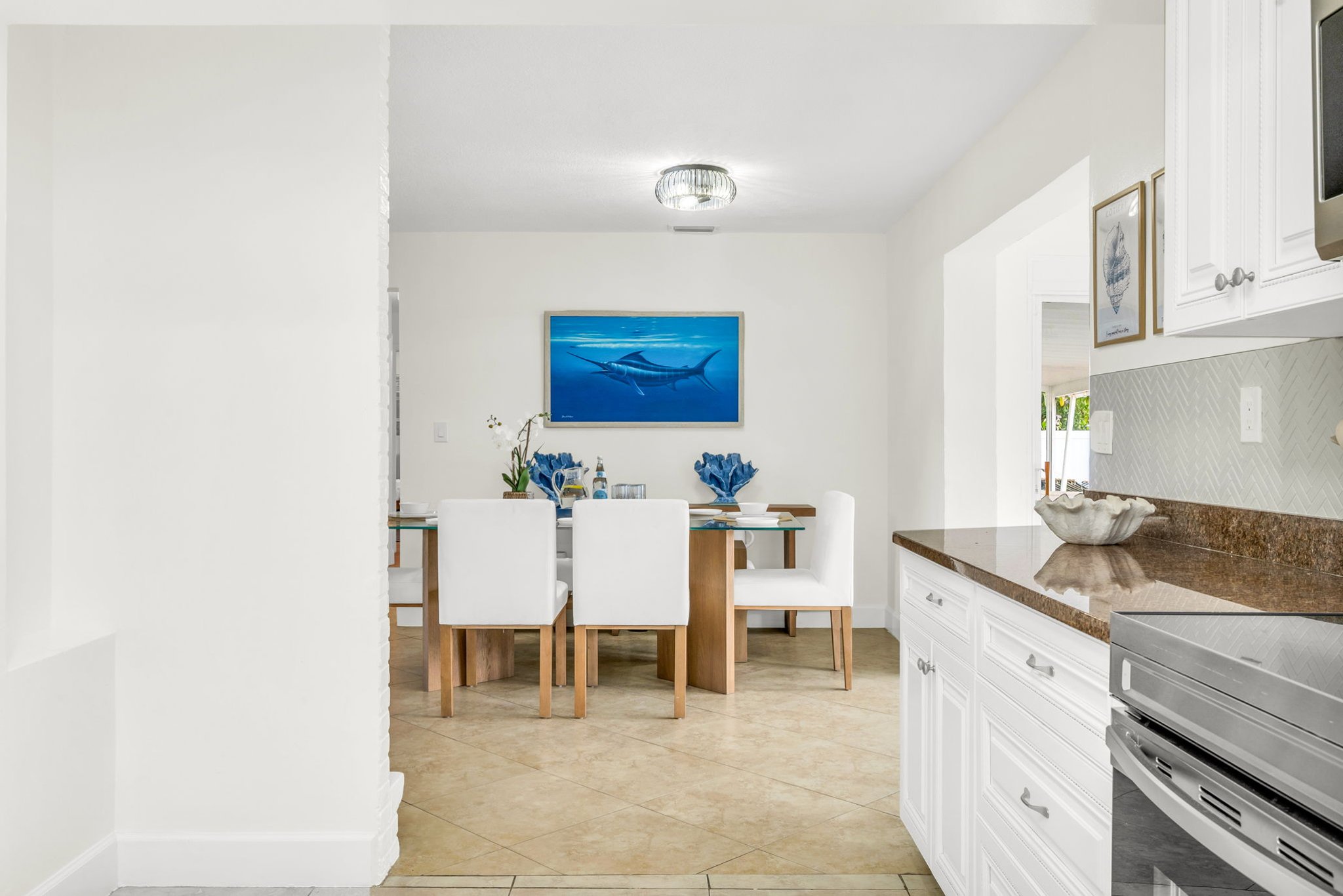 Enjoy meals together in this stylish dining space with seating for six, ocean-inspired artwork, and plenty of natural light flowing in from the adjoining sunroom.
